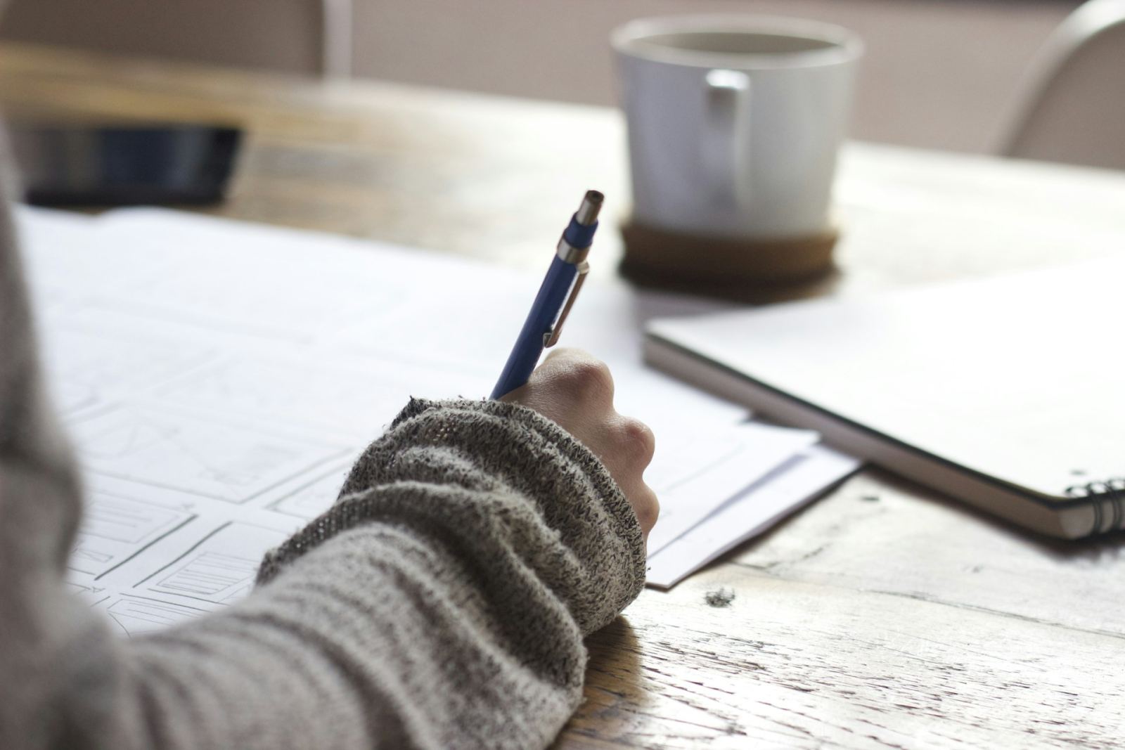 Hand writing notes at a desk